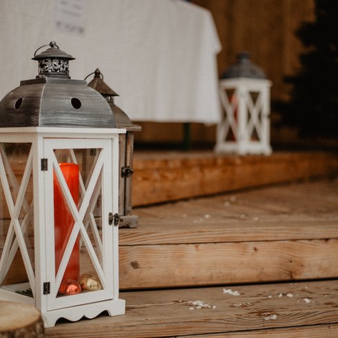 Smaragdhotel Tauernblick – Ihr 4-Sterne-Hotel am Wildkogel Weißer Laternenwindschutz mit roter Kerze auf Holzstufen