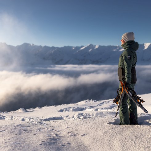 Smaragdhotel Tauernblick – Ihr 4-Sterne-Hotel am Wildkogel Person mit Schneeschuhen steht auf schneebedecktem Gipfel mit Bergpanorama