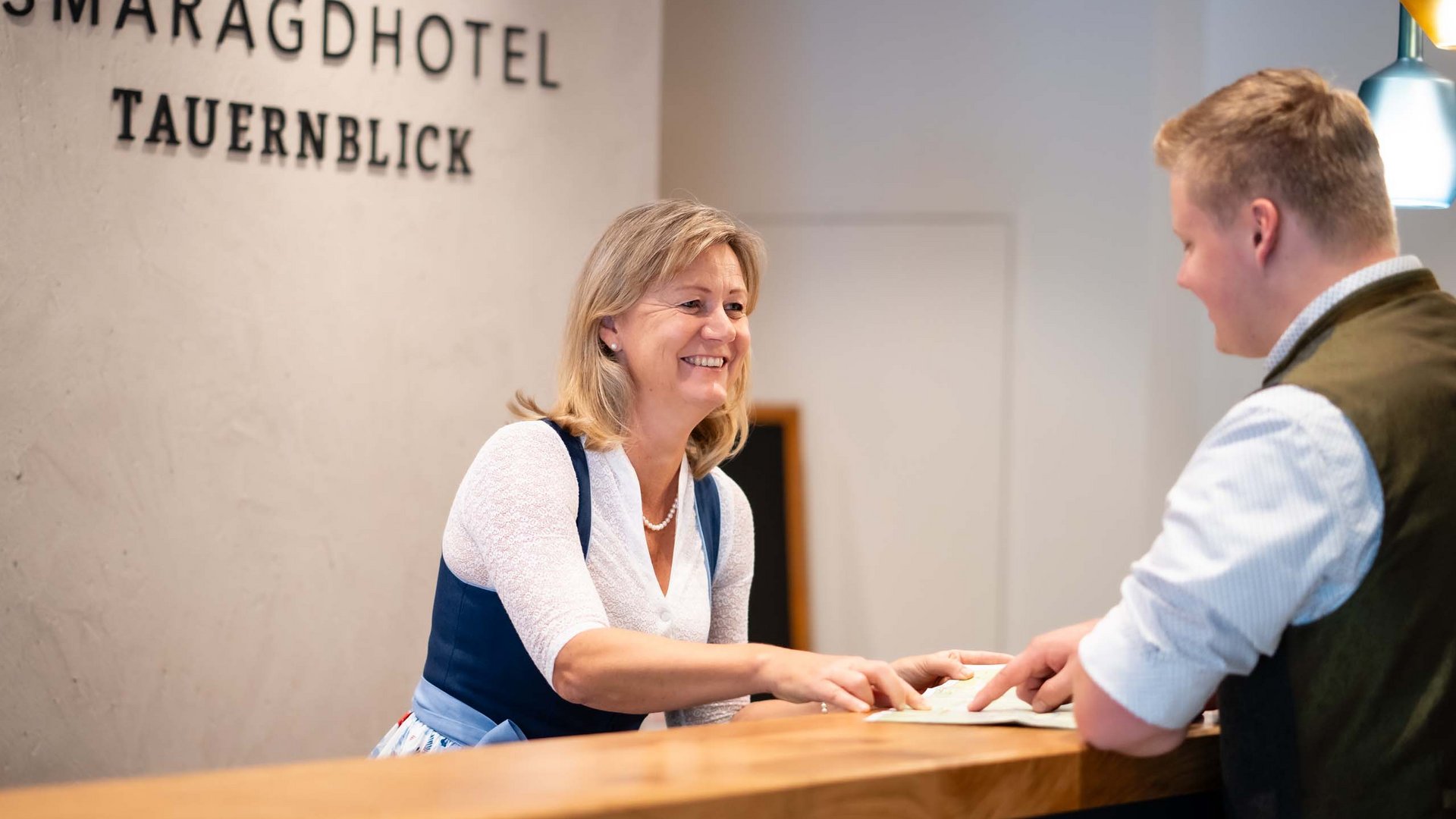 Smaragdhotel Tauernblick – Ihr 4-Sterne-Hotel am Wildkogel Rezeptionistin begrüßt Gast im Smaragdhotel Tauernblick