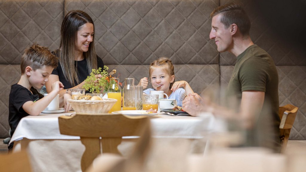 Smaragdhotel Tauernblick – Ihr 4-Sterne-Hotel am Wildkogel Familie mit zwei Kindern isst gemeinsam am gedeckten Tisch in gemütlichem Raum