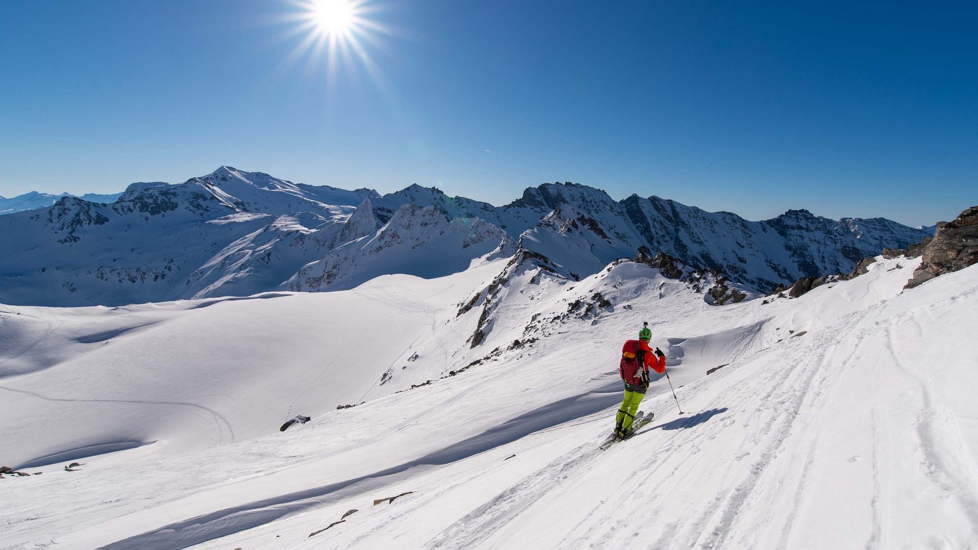 Smaragdhotel Tauernblick – Ihr 4-Sterne-Hotel am Wildkogel Skifahrer in bunter Ausrüstung fährt auf schneebedecktem Hang unter Sonne und blauem Himmel
