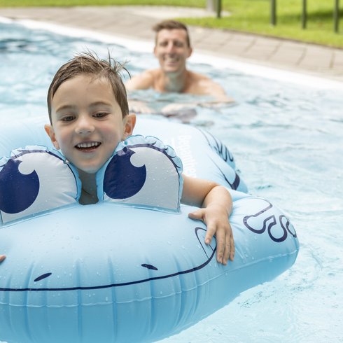 Smaragdhotel Tauernblick – Ihr 4-Sterne-Hotel am Wildkogel Junge mit blauem Tier-Schwimmreifen und Mann im Pool im Hintergrund